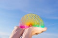 Plastic rainbow toy in hands on a background of blue sky.