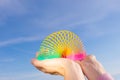 Plastic rainbow toy in hands on a background of blue sky.