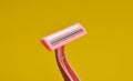Plastic razor for depilation close-up on a yellow background
