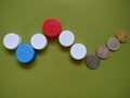 Plastic recycling concept generating finance profit. Caps and coins on green background