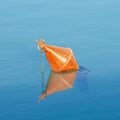 Plastic red bouy on a calm lake isolated on blue background Royalty Free Stock Photo