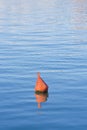 Plastic red bouy on a calm lake isolated on blue background Royalty Free Stock Photo