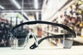 Plastic safety goggles, on the table and background of the hardware store with tools. Royalty Free Stock Photo