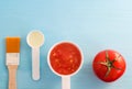 Plastic scoops with tomato puree and olive oil. Ingredients for preparing homemade facial mask. DIY cosmetics recipe.