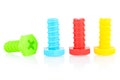 Plastic screws of different colors are arranged in a row on a white background. Children`s toys for the development of fine motor