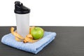 Plastic shaker, apple, measures tape on blue towel on mat