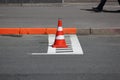 Plastic signaling traffic cone encloses a place in the parking lot for cars.