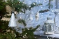 Plastic silver colored bell on evergreen tree on background of snowing and lamp on the porch.