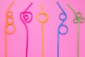 Plastic spiral multicolor tubes on pink paper card. Abstract colorful background of curved cocktail straws. Laconic design. Concep Royalty Free Stock Photo