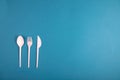 Plastic spoon, fork and knife on blue background flat lay. Horizontal image Royalty Free Stock Photo