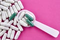 Plastic spoon and green and white pills on pink background Royalty Free Stock Photo