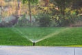 Automatic garden lawn sprinkler in action watering green grass Royalty Free Stock Photo