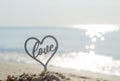 Plastic stick in shape of heart and word Love in sand on beach seashore Royalty Free Stock Photo