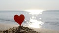 Plastic stick shape red heart sand sandy beach sea shore background of sea waves