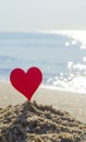 Plastic stick in shape of red heart in sand on sandy beach of sea shore Royalty Free Stock Photo
