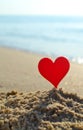 Plastic stick in shape of red heart in sand on sandy beach of sea shore
