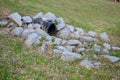 plastic storm water outlet with rip-rap protruding from a grass embankment Royalty Free Stock Photo