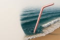 A plastic straw inserted into the ocean. Space for text. Royalty Free Stock Photo