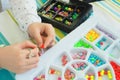 Plastic substrates with multi-colored beads and the hands of a girl making a bracelet. handmade Royalty Free Stock Photo