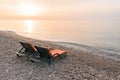 Plastic sun beds with orange capes on the sea beach at sunrise. Summer vacation concept.