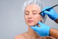 Plastic surgery. Doctor drawing perforation lines on woman`s face Royalty Free Stock Photo