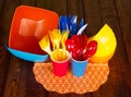 Plastic tableware: bowls, forks, spoons, knives, cups on dark wood. Royalty Free Stock Photo