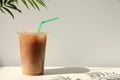 Plastic takeaway cup of delicious iced coffee on white table under sunlight, space for text Royalty Free Stock Photo