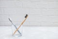 Plastic toothbrush and eco-friendly bamboo toothbrush in a glass cup on grey neutral background Royalty Free Stock Photo