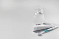 Plastic toothbrush with paste and glass of water on grey background, space for text Royalty Free Stock Photo