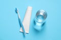 Plastic toothbrush with paste and glass of water on light blue background, flat lay Royalty Free Stock Photo