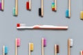 Plastic toothbrush surrounded by bamboo toothbrushes on grey background Royalty Free Stock Photo