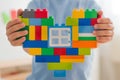 Plastic toy blocks, designer of children`s toys. Bright building blocks in the shape of a heart in children`s hands. Royalty Free Stock Photo