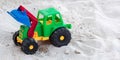 A plastic toy bulldozer color green, red, yellow and blue with black big wheels placed on a white sand in a beach resort Royalty Free Stock Photo