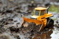 plastic toy bulldozer pushing a mound of wet soil