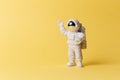 Plastic toy figure astronaut on a yellow background. Copy space. Close-up. The concept of space and space flights