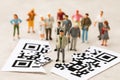Plastic toy men and a sheet torn in half with a barcode, the concept of a rally of people against the introduction of the QR code