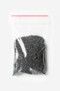 Plastic transparent zipper bag with half poppy seeds isolated on white, Vacuum package mockup with red clip. Concept.