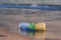Plastic trash - bottle and bags in sea water near the shore in the golden light of dawn. Ocean plastic pollution concept