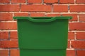 Plastic trash can green object for cleaning with empty space for copy or your text here on brick wall background texture