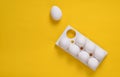 Plastic tray with white eggs and on a yellow pastel background, minimalism trend, top view. Royalty Free Stock Photo