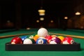Plastic triangle rack with billiard balls and cues on green table indoors, space for text Royalty Free Stock Photo