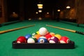 Plastic triangle rack with billiard balls and cues on green table indoors, space for text Royalty Free Stock Photo