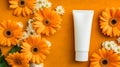 a plastic tube of cream set against an orange background adorned with vibrant gerbera flowers. Royalty Free Stock Photo