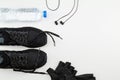 Plastic water bottle, black sport shoes, glove and headphone on white background