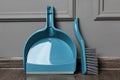 Plastic whisk broom with dustpan near grey wall indoors