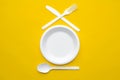 Plastic white fork, knife, spoon and plate on yellow background. Cooking utensil. Top view. Minimalist Style. Copy, empty space Royalty Free Stock Photo