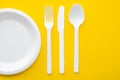 Plastic white fork, knife, spoon and plate on yellow background. Cooking utensil. Top view. Minimalist Style. Copy, empty space Royalty Free Stock Photo