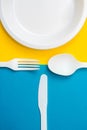 Plastic white fork, knife, spoon and plate on yellow and blue background. Cooking utensil. Top view. Minimalist Style. Copy, empty Royalty Free Stock Photo