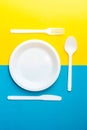 Plastic white fork, knife, spoon and plate on yellow and blue background. Cooking utensil. Top view. Minimalist Style. Copy, empty Royalty Free Stock Photo