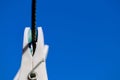 White plastic clothespins clothes pegs hanging from twisted wire laundry line Royalty Free Stock Photo